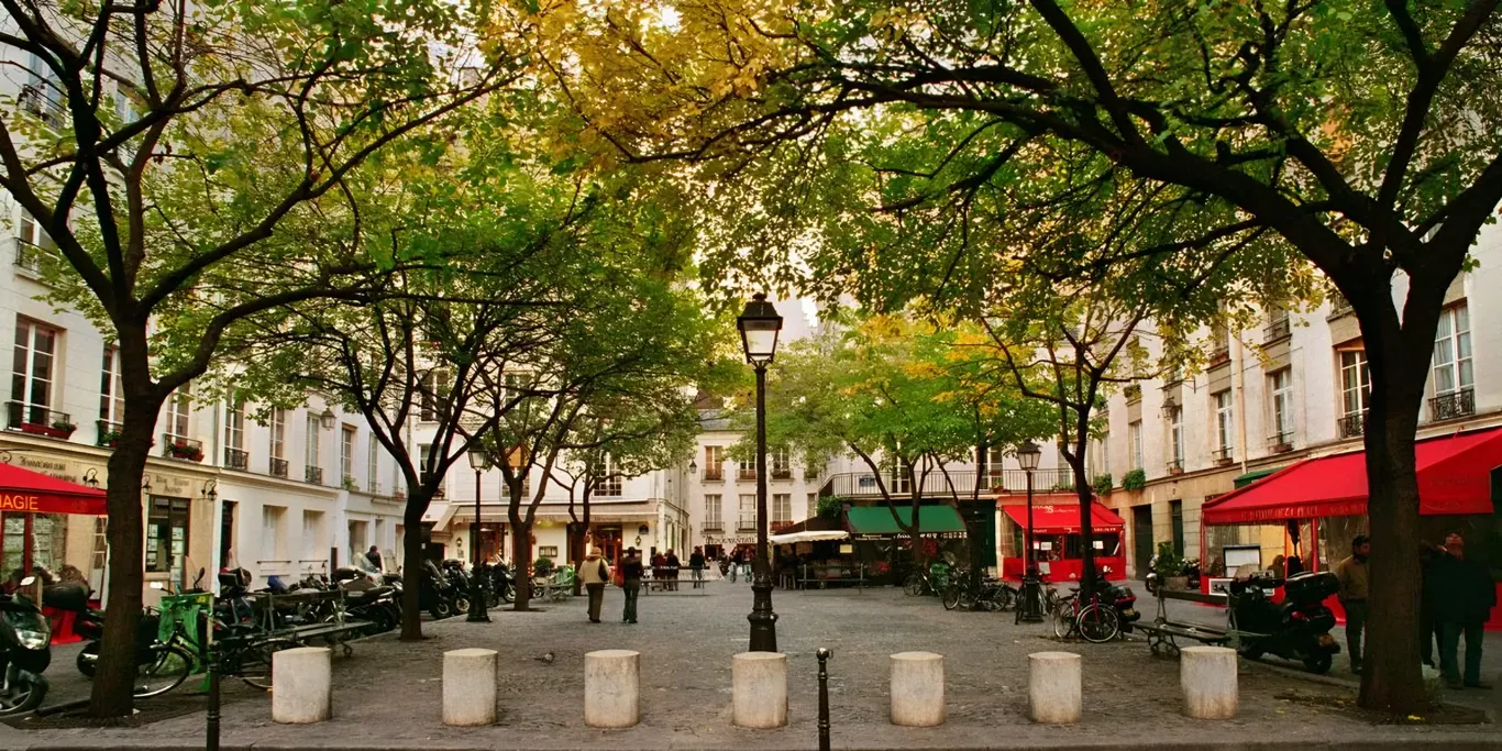 Pleintje met bomen en rode luifels van cafes in Le Marais in Parijs