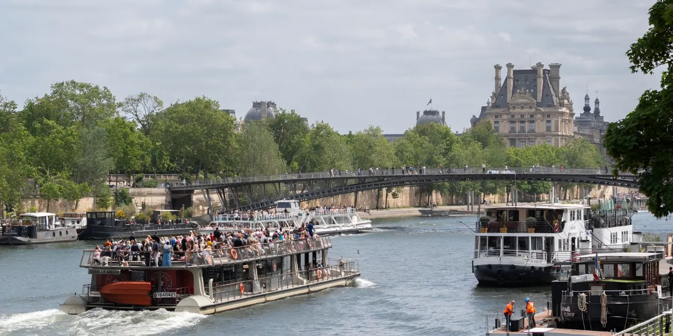 Rondvaartboten op de Seine in Parijs met het Louvre en de Passerelle Solferino op de achtergrond