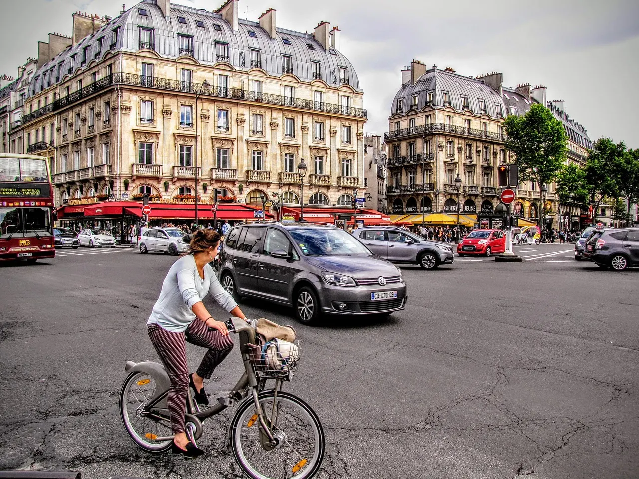Fietser op een deelfiets steekt een kruispunt over in Parijs met haussmanngebouwen op de achtergrond