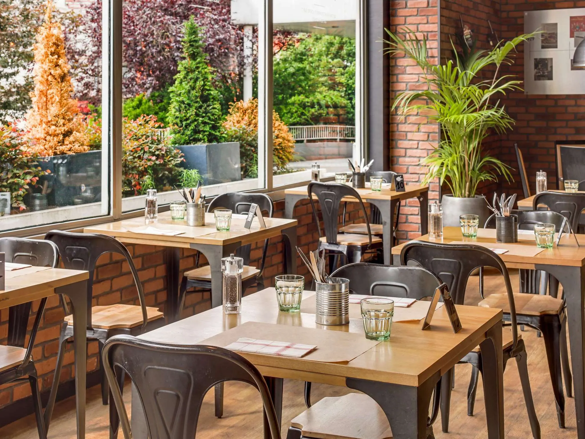 Ontbijtzaal met houten tafels en grote ramen in een hotel in Parijs