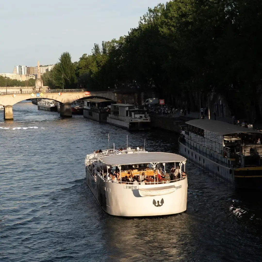 Rondvaartboot op de Seine in het late middaglicht met passagiers op het bovendek
