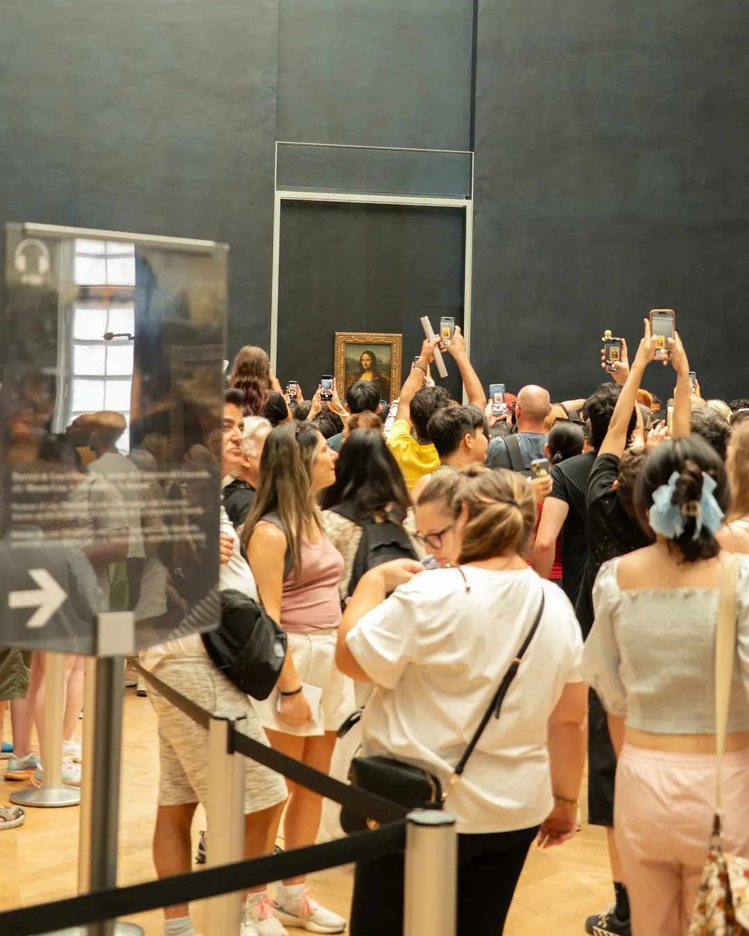 Bezoekers maken een foto van de Mona Lisa onder begeleiding van museumpersoneel