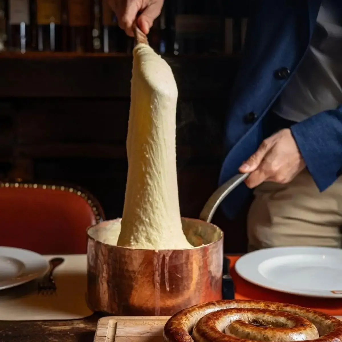 Aligot wordt uit de koperen pan getrokken bij Ambassade d Auvergne in Parijs