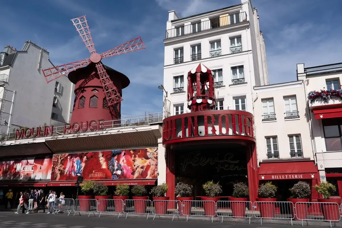 Bezoekers wachten achter de dranghekken voor de ingang en de billetterie van de Moulin Rouge
