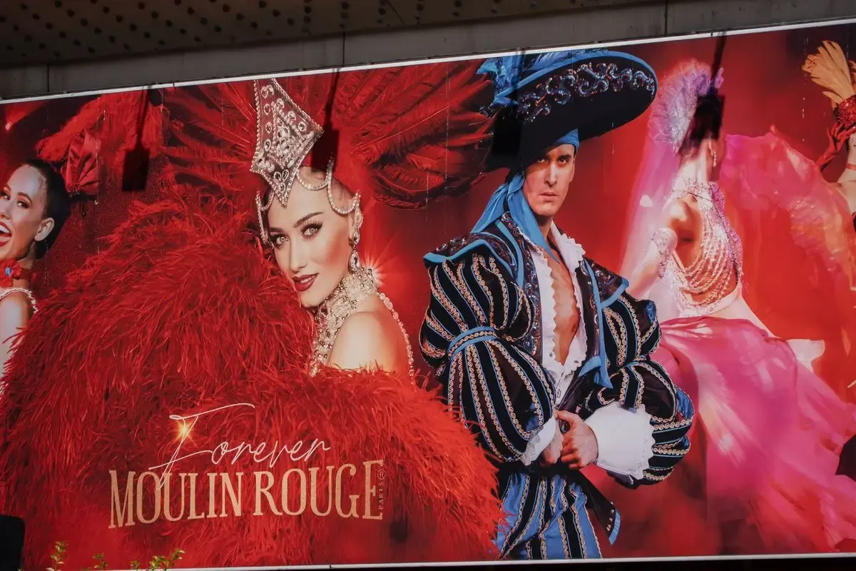 Affiche van de Moulin Rouge met dansers in veren en pailletten aan de gevel