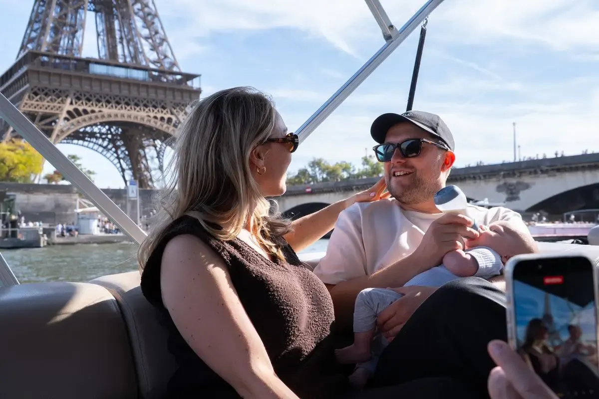 Een gezin proost met een fles bubbels aan boord van een eigen boot op de Seine bij de Eiffeltoren