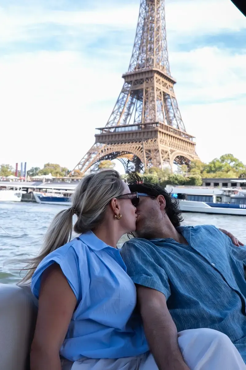Een stel aan boord van een eigen boot op de Seine met de Eiffeltoren op de achtergrond